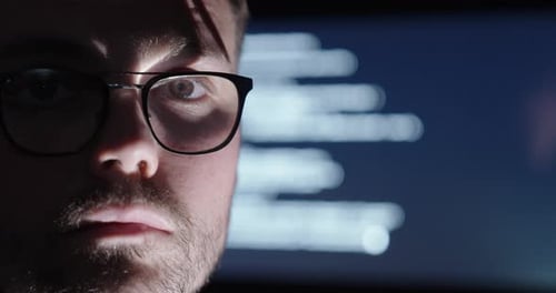 man with glasses nodding, with an AI display behind him showing code or writing.