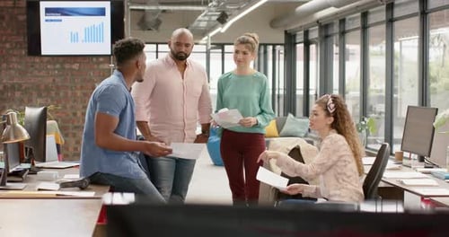 Diverse creative business colleagues with documents in discussion at casual office, in slow motion