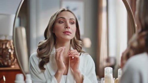 Woman in White Robe Looks in Mirror