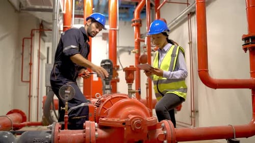 Wide shot of engineer or technician worker discuss about red pipe and machine system in site