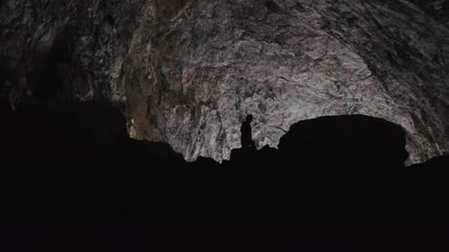 Cave explorer in a dark cave. Caver. Silhouette of a caver. Natural void. Spelunking. Speleology. Ad