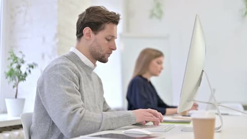 Focused Man Working on Computer in Bright Office