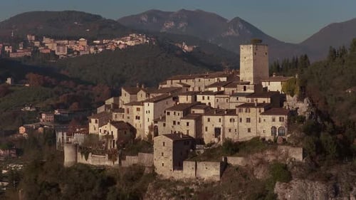 Aerial view of buildings on hill with mountains, Italy.