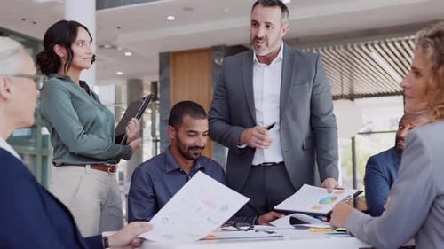Successful Entrepreneur Focusing on Work with Charts During Meeting with Multiethnic Employee