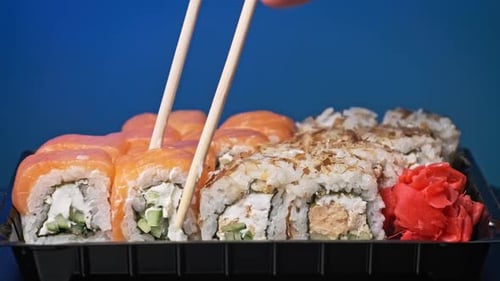 Sticks Take Sushi From the Plastic Sushi Box CloseUp