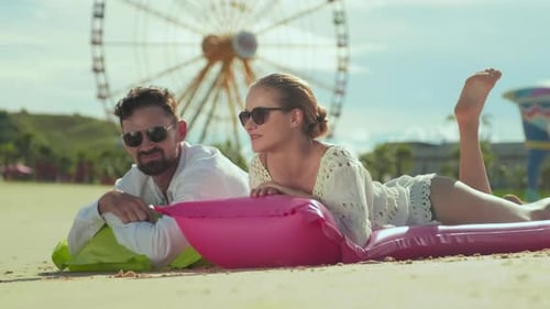 Young Restful Couple Relaxing on Inflatable Mattresses on Sandy Beach