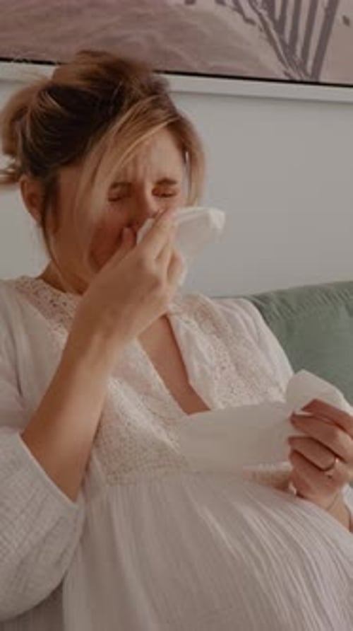 Pregnant Woman Crying and Wiping Nose with Tissue