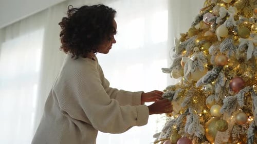 Woman Decorating Christmas Tree with Gold Ornaments