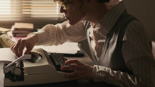 Konzentrierte Autor mit Retro-Brillen arbeitet an Schreibmaschine