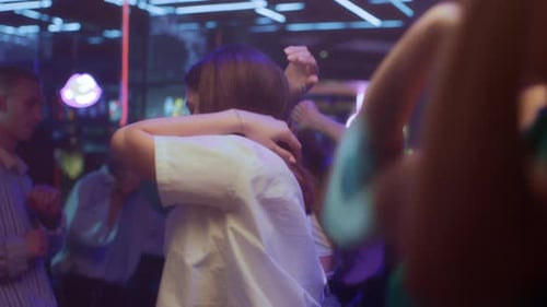 Group of Young Friends Dances Together in Neon Light of Night Club
