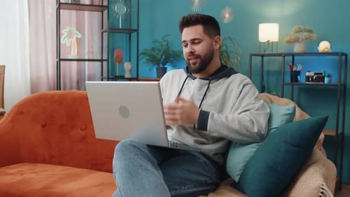 Bearded Man Video Conferencing on Laptop at Home