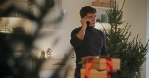 Man Answers Phone Next to Christmas Tree