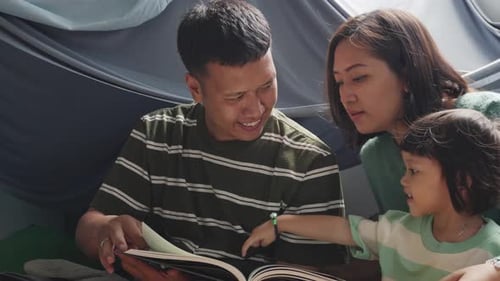 Family Reading a Book in Tent Together