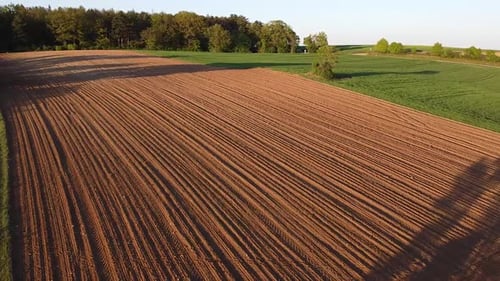 Drone flight over some fields in spring with forest in the background