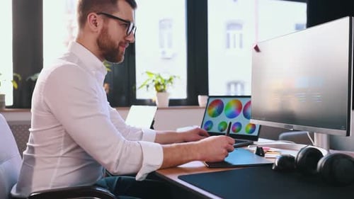 Man Creates Graphic Designs in Modern Office