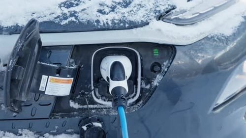 Man Plugging in Electric Car Charger in Winter