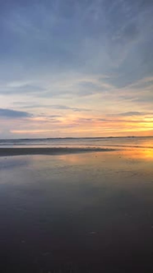 vertical video of beautiful views of the sunset on the beach with small waves, natural panoramas
