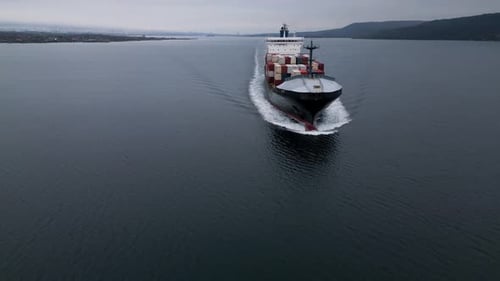 Aerial View of Large Container Ship Moving Across Calm Sea Leaving Wake Behind Cargo Vessel