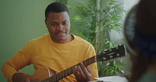 Young Adult Playing Acoustic Guitar at Home