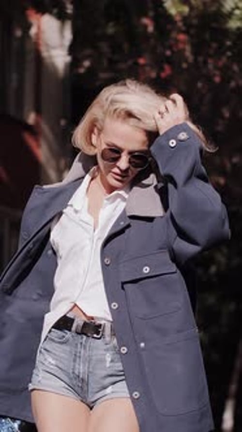 Attractive senior woman walking down the street with flying hair. Happy relaxed lady walking.