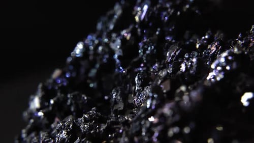 Glowing gemstones in solid dark rock piece isolated on black background