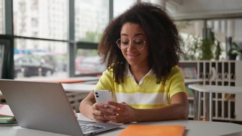 Young Adult Working on Laptop with Mobile Phone