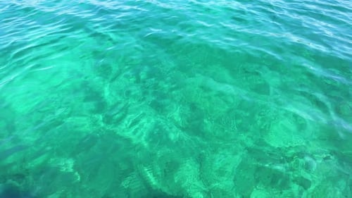Emerald ocean sea water color texture up-close, sunshine reflection calm moving