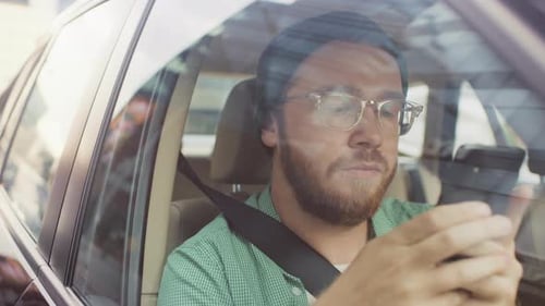 Stylish Young Man Riding in a Car, Sitting on a Passenger Seat Uses Smartphone, types Message, Brow