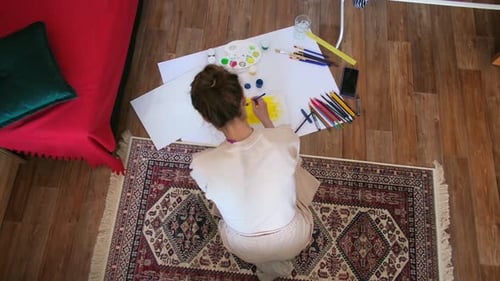 Woman Sits on Rug and Paints Sun with Brush