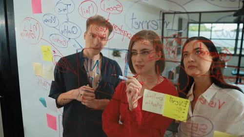 Team Brainstorming Together Writing on Glass Whiteboard