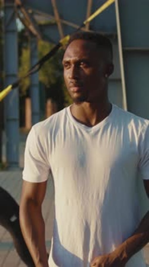 Athletic man with fitness straps smiles outdoors