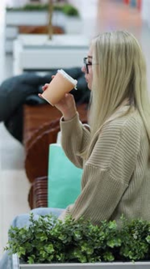 Career Woman Sipping Tea Reflecting with Decorative Plants in Mall