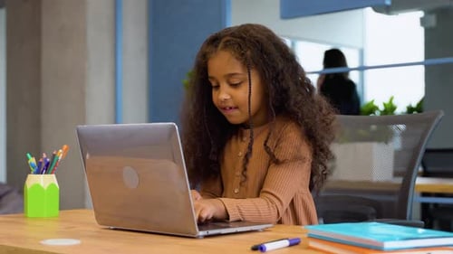 Cheerful Black Student Girl Doing Her Homework Using Laptop in Primary School