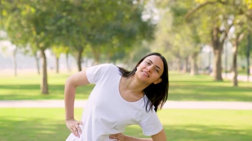 Young Woman Stretching in a Sunny Park