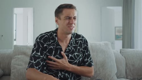Man Experiencing Chest Pain While Sitting on Couch
