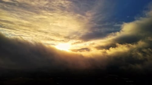 Goldener Sonnenuntergang, der durch neblige Wolken in einer ruhigen und dramatisch Himmelsszene bricht