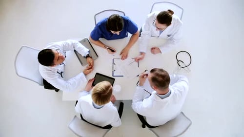 Doctors discuss medical report on tablet computer at hospital meeting