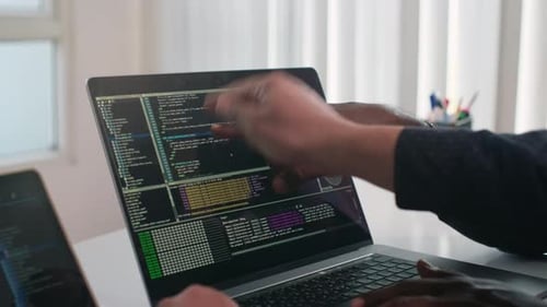 Two People Reviewing Computer Code on Laptop