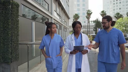 Video of Doctors and nurses walking and discussing patient case using a tablet outside hospital