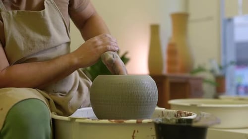 Potier mâle finissant un pot de fleurs en argile tournant sur une plaque tournante en poterie, gros plan dans l'atelier