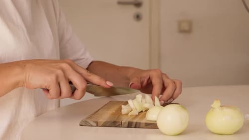 Woman Dices Onions on Wooden Cutting Board