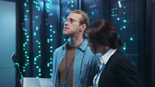 A Man and Woman Collaborate in a Server Room Analyzing Data