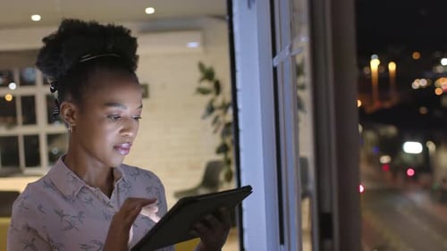 Young African American woman works late in a business office, with copy space