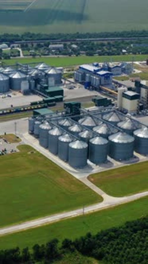 Agricultural industry. Modern factory on green field with steel elevators.