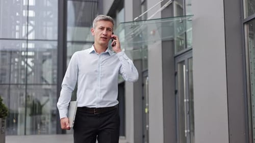 Geschäftsmann telefoniert vor dem Bürogebäude