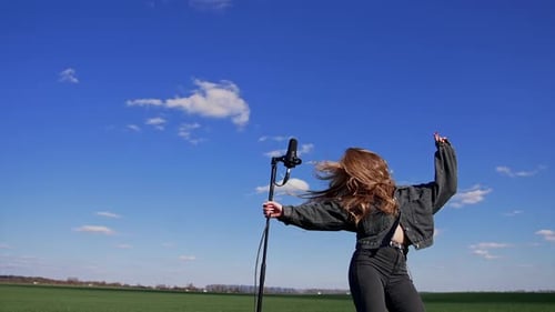 Young rock star dancing near microphone outdoors.