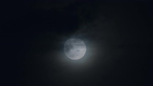 Dramatic Full Moon Ascending Through Night Clouds