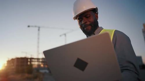 Focused African Foreman Looking at Laptop Display at Construction Site Portrait of Black
