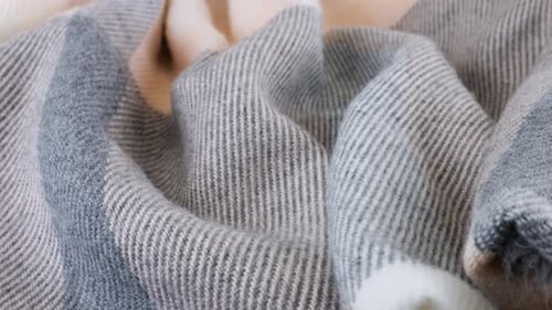 Top view of the soft folds of wool fabric in pastel gray-pink colors rotated on the display case.