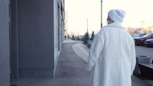 Woman Joyfully Strolling Through a Bustling City Street in Winter Attire